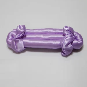 Lilac satin heatless curling rod with bows on both ends, placed on a plain background